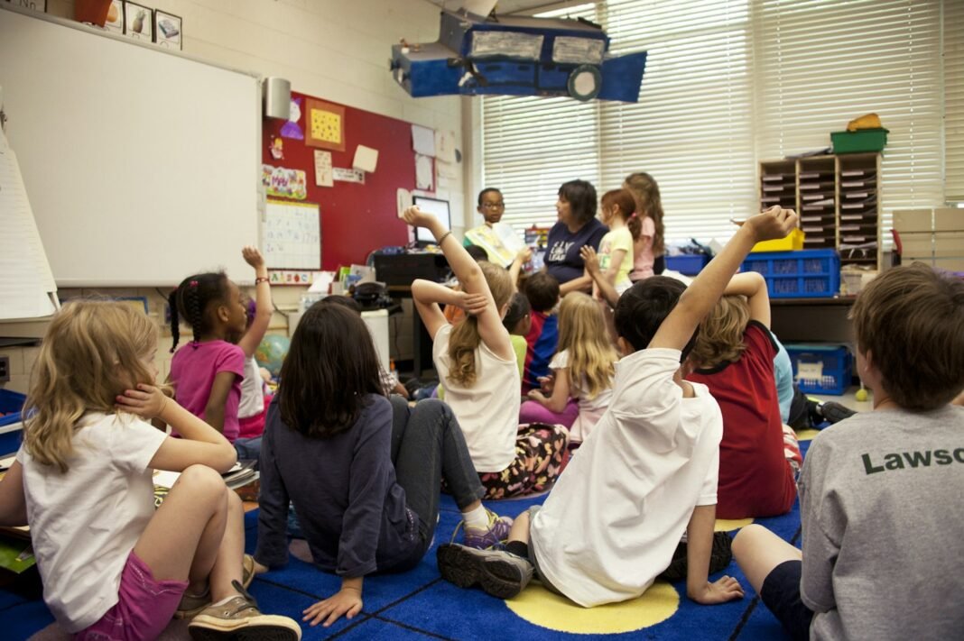 Preschool-age children sitting on the floor with a teacher