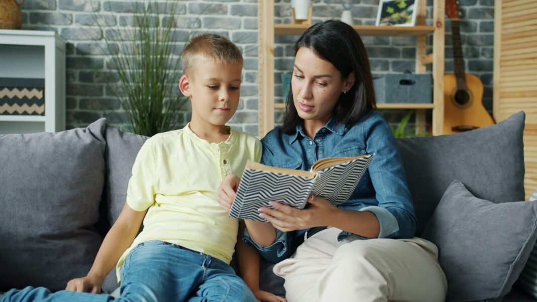 A mother and young son reading a book together on the couch