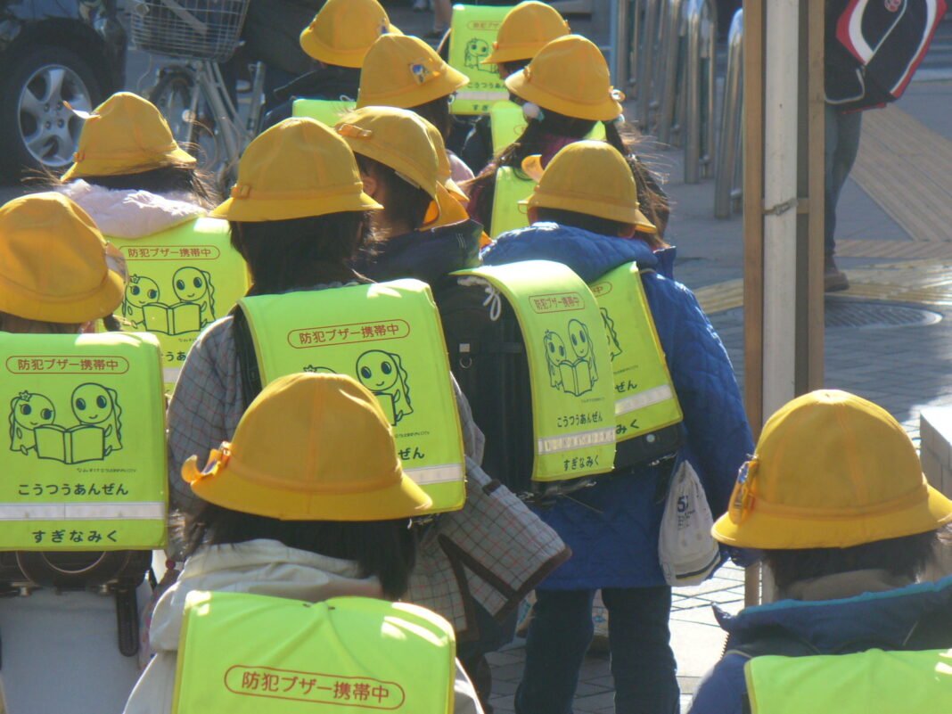 Elementary schoolchildren in yellow hats with randoseru school bags walking in Kugayama, Tokyo